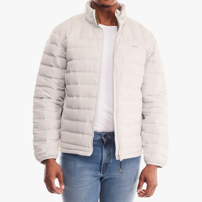 A man wears a light grey Jeep men's down puffer jacket, featuring a full zipper and a high collar, with blue jeans.