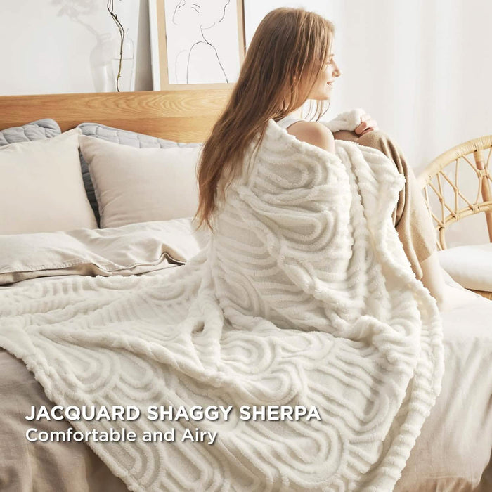 GentleSoft Arch Shaggy Sherpa Fleece Blanket, cream, plush texture with raised arch pattern, woman on bed.