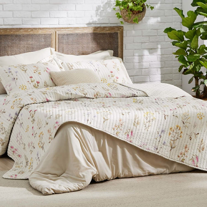 Autumn wildflower quilt set with multicolor floral print, quilted texture, and rattan headboard.