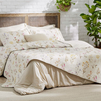 Autumn wildflower quilt set with multicolor floral print, quilted texture, and rattan headboard.