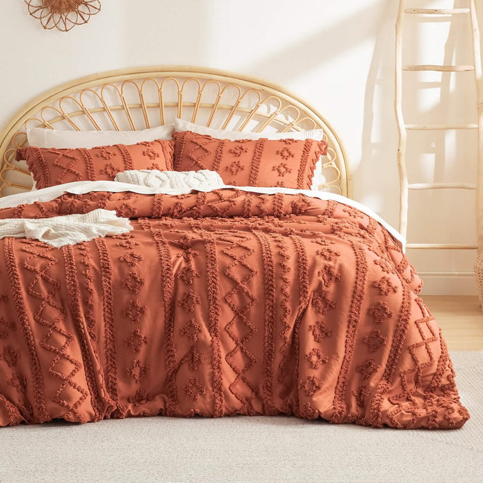 Burnt orange boho comforter set with diamond and line embroidery, includes two pillow shams, on a bed with rattan headboard.
