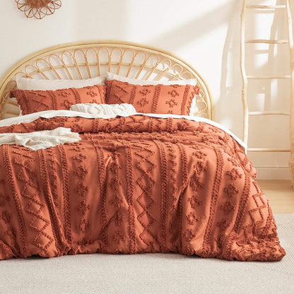 Burnt orange boho comforter set with diamond and line embroidery, includes two pillow shams, on a bed with rattan headboard.