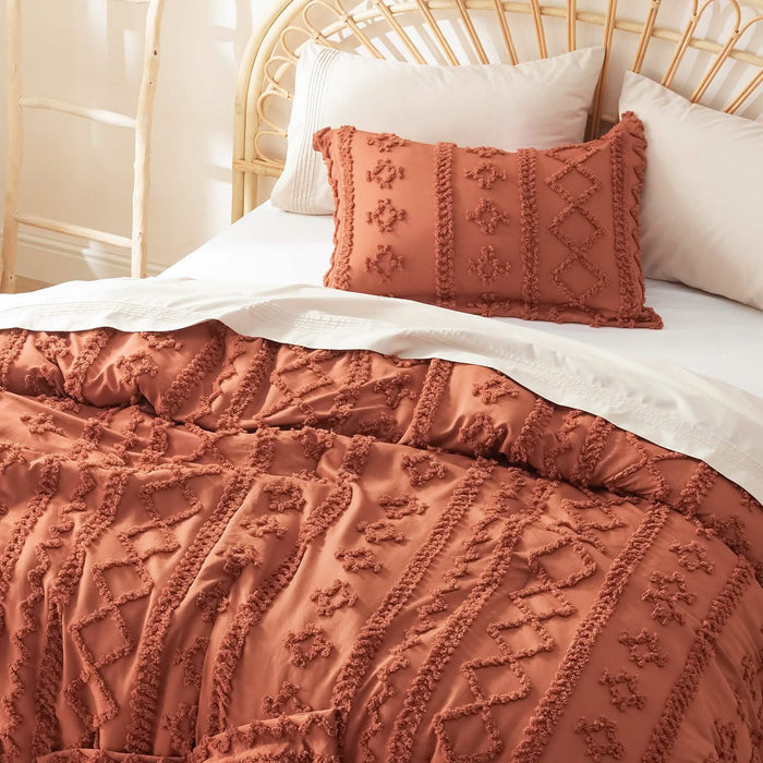 Soft burnt orange boho microfiber comforter set with diamond and line embroidered tufting on a bed with rattan headboard.