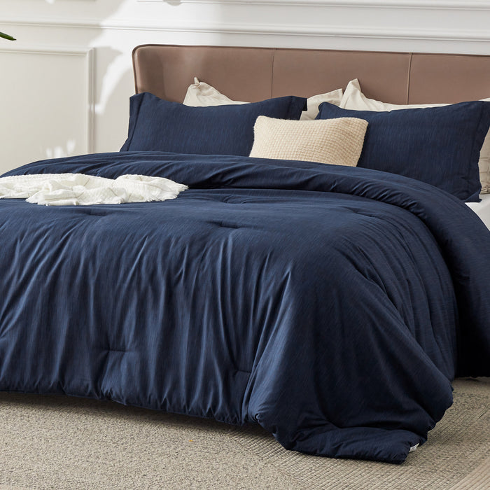 Navy blue GentleSoft comforter set with dual-tone texture, on a bed with decorative pillows and throw blanket.