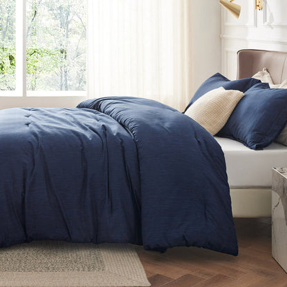 Navy blue GentleSoft comforter set with dual-tone texture on a bed, includes two pillow shams and a cream decorative pillow.