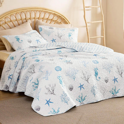GentleSoft Chill Vibes Quilt Set with blue and grey seashells, starfish, seahorses on white background, bedroom setting.