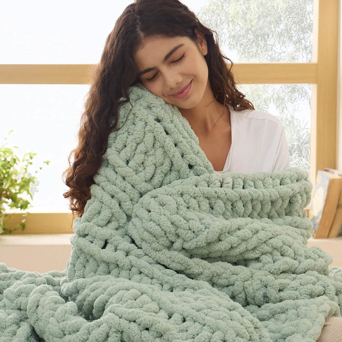 Sage green chunky knit chenille blanket with visible braided texture held by woman for cozy home decor.