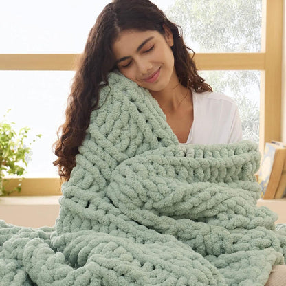 Sage green chunky knit chenille blanket with visible braided texture held by woman for cozy home decor.