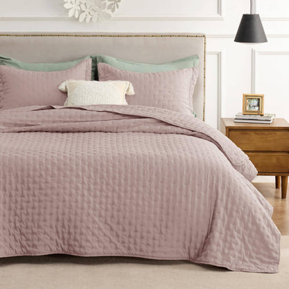 GentleSoft Clover Ultrasonic Quilt Set in rose with embossed pattern on a made bed, styled with green and cream pillows.
