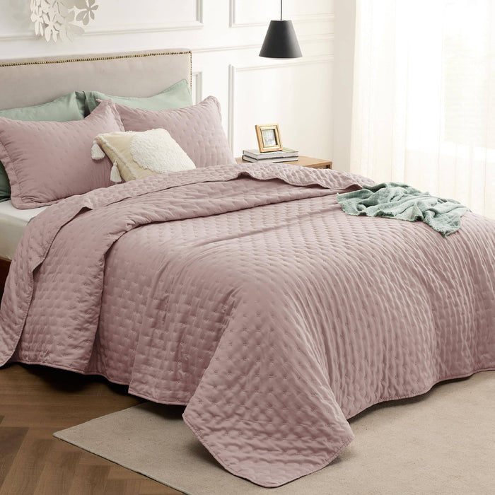 GentleSoft Clover Quilt Set in rose with embossed pattern and ultrasonic binding on a styled bed.