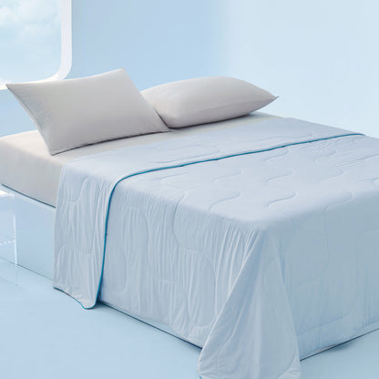 Light blue GentleSoft cooling blanket draped on a bed with grey pillows. Smooth nylon texture.