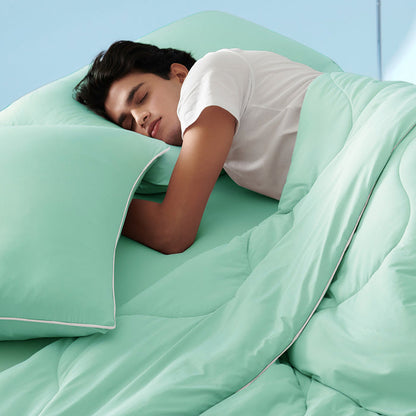 GentleSoft Cooling Comforter Set in mint green, soft fabric with white piping, man sleeping peacefully.