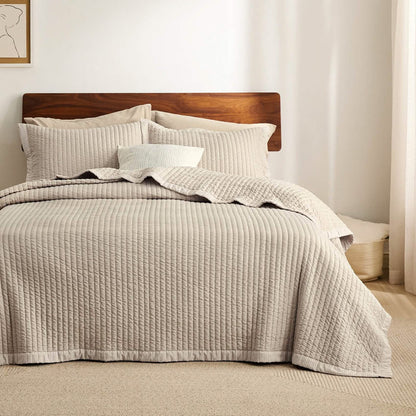 Beige corduroy quilt set with channel stitching and stripe pattern on a bed, styled with shams for bedroom decor.