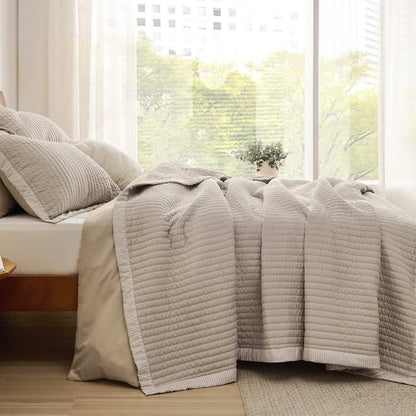 GentleSoft beige corduroy quilt set on wooden bed, featuring channel stitching and striped border, styled with shams.