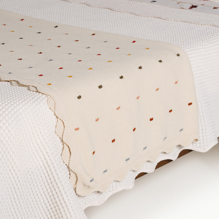 Ivory@Scalloped cotton throw draped across a bed