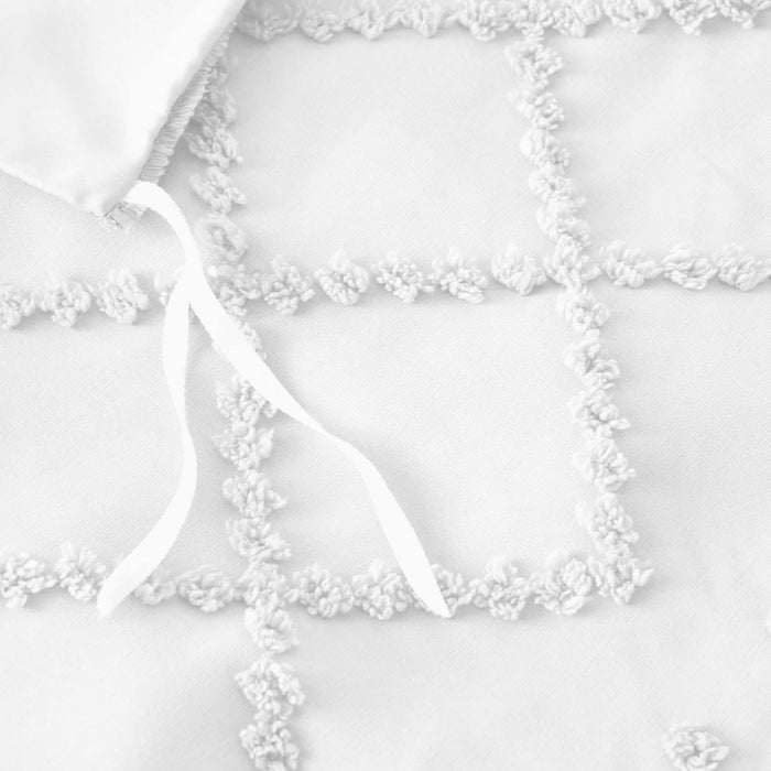 Close-up of white boho duvet cover showing tufted geometric embroidery and interior corner tie detail.