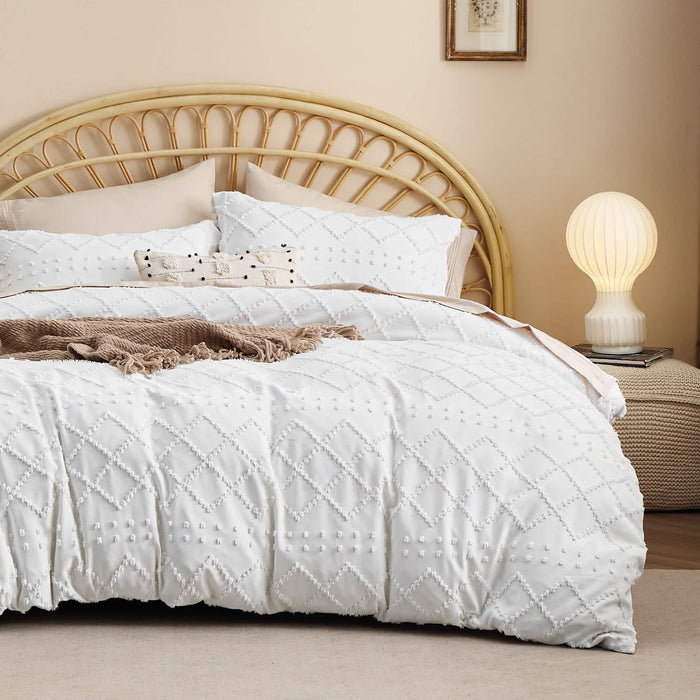 White boho duvet cover and pillow shams with diamond tufted embroidery on a bed with rattan headboard.