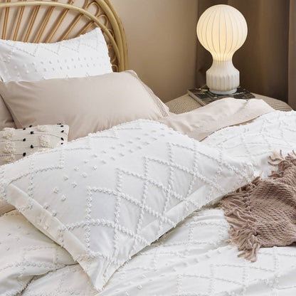 White boho duvet cover and pillow shams with raised diamond tufted embroidery on a bed.