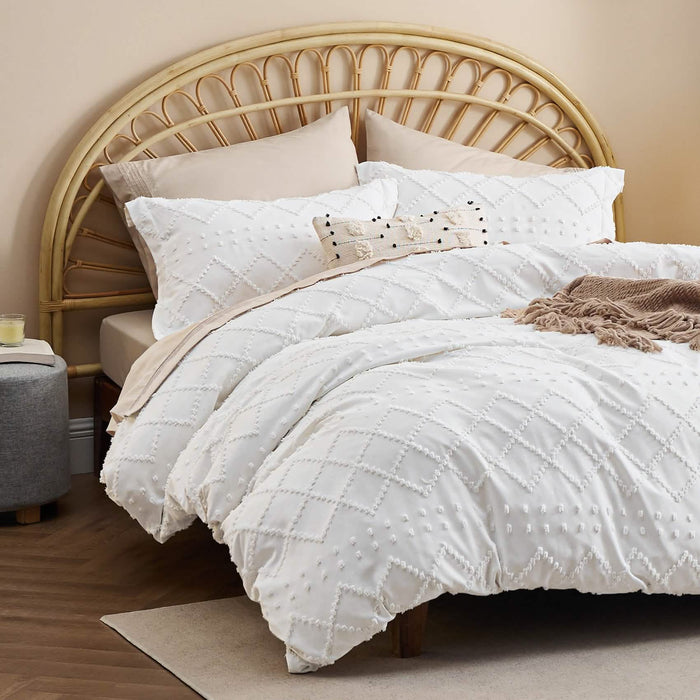White boho duvet cover and shams with diamond tufted texture on a bed with rattan headboard.
