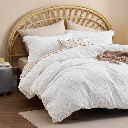White boho duvet cover and shams with diamond tufted texture on a bed with rattan headboard.