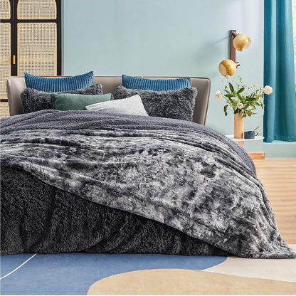 Dark grey reversible GentleSoft Faux Fur Sherpa blanket draped on a bed, showcasing plush texture and cozy feel.
