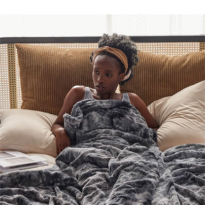 Woman wrapped in marbled dark grey GentleSoft faux fur Sherpa blanket on bed, showcasing plush texture and cozy feel.