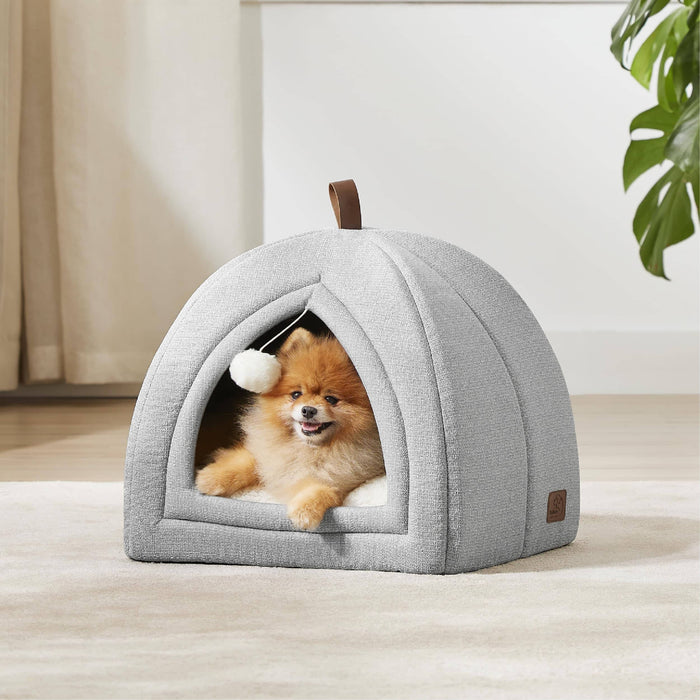 Light gray faux-linen pet tent with Pomeranian dog peeking out, featuring pom-pom toy and leather handle.