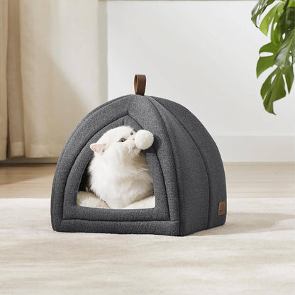 Dark gray faux-linen cat tent, fluffy white cat plays with pom-pom toy inside. Plush interior, faux-leather handle.