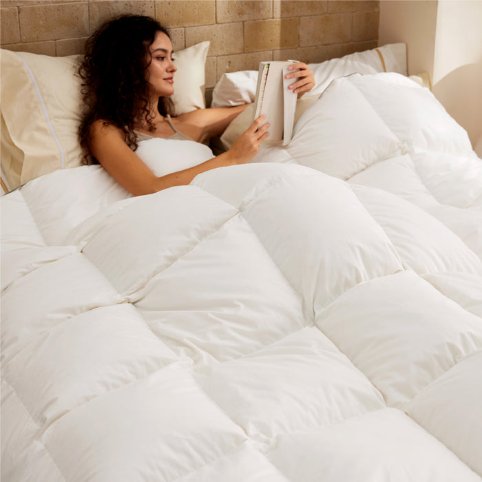 PureWoven feather down comforter with plush box quilting, woman reading in bed.