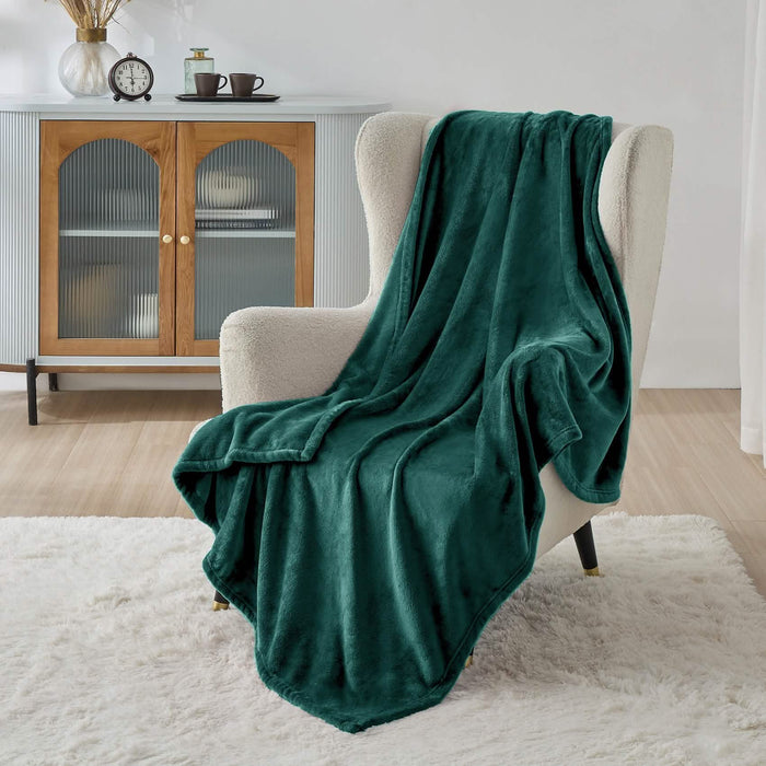 Forest green GentleSoft flannel fleece blanket draped on cream armchair, plush texture.