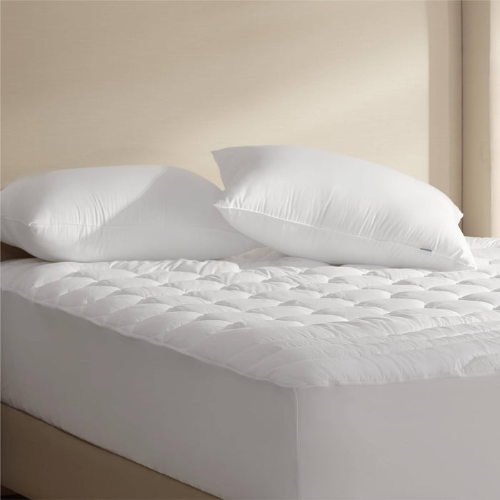 Two white GentleSoft Hotel Pillows with puffy support on a quilted mattress topper, suggesting comfort.