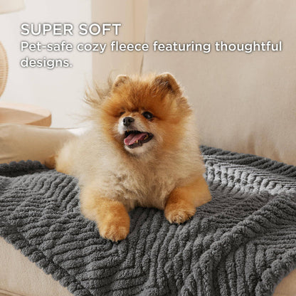 Dark grey jacquard fleece pet blanket with chevron pattern protecting a light sofa with a fluffy Pomeranian resting on it.