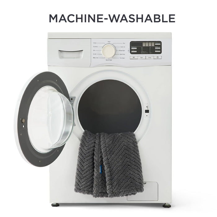 Dark grey chevron jacquard fleece pet blanket draped over an open washing machine door, highlighting easy-care feature.