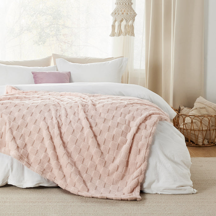 GentleSoft Jacquard Shaggy Sherpa Blanket in light pink, draped on a bed, highlighting plush texture and checkerboard weave.