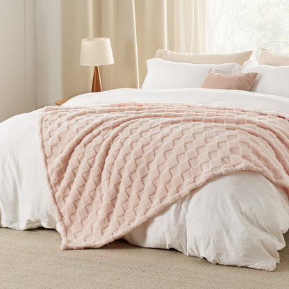 GentleSoft Jacquard Sherpa Blanket in light pink draped on a bed, showing plush texture and checker pattern.