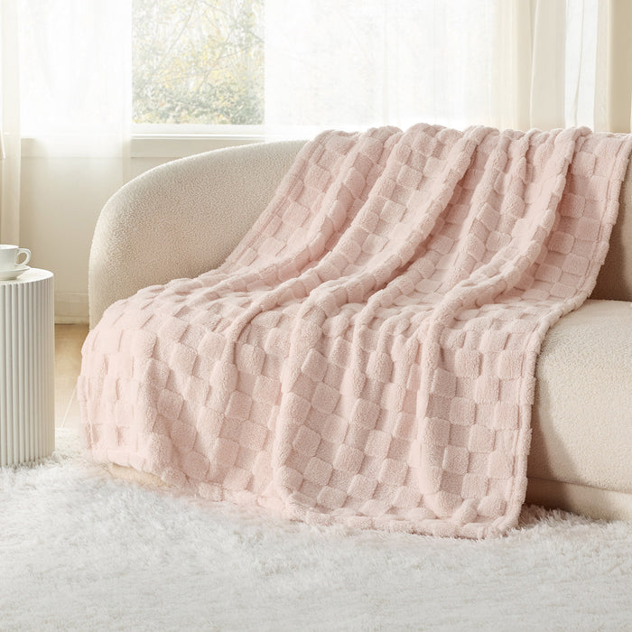 GentleSoft Jacquard Shaggy Sherpa Blanket in light pink, draped on a sofa, showcasing plush texture and checker pattern.