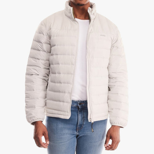 A man wears a light grey Jeep men's down puffer jacket, featuring a full zipper and a high collar, with blue jeans.