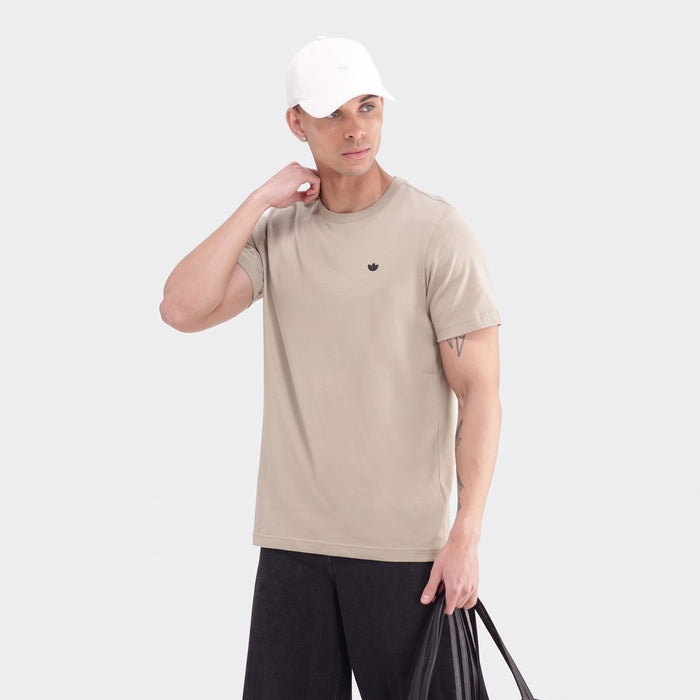 Men's Adidas Essential Tee in khaki, featuring a small black logo, paired with black shorts and a white cap, held by a male