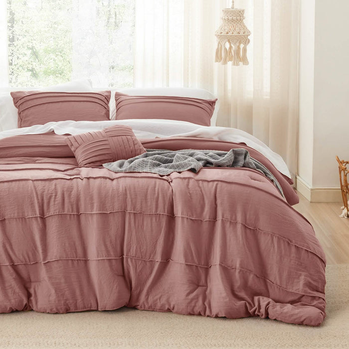 Rose pink GentleSoft pinch pleat comforter set with decorative pillow and pillowcases on a bed.