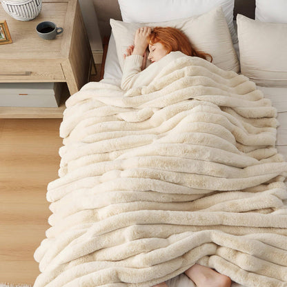 GentleSoft plush cream striped blanket 50"x70" on bed, woman sleeping peacefully under its cozy faux fur coverage.