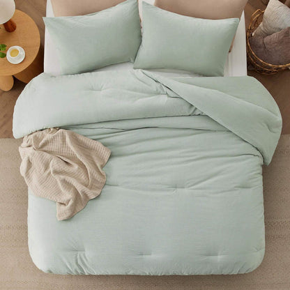 Pale green GentleSoft prewashed cotton comforter set with wrinkled texture on a bed, styled with accent pillows and throw.