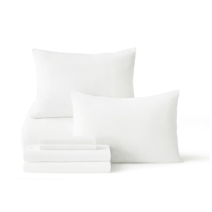 White prewashed down alternative bed-in-a-bag components: pillows and folded sheets.