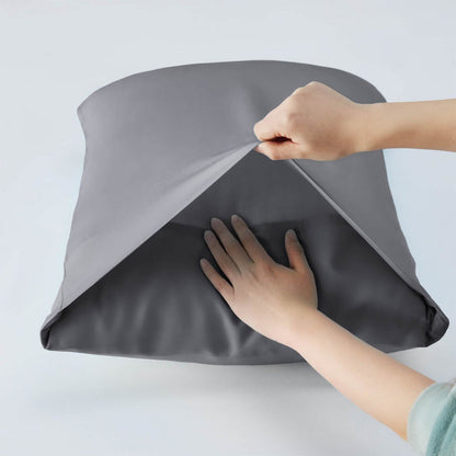 Hands feel the smooth, cool texture of charcoal grey GentleSoft rayon bamboo pillowcases, showcasing material quality.