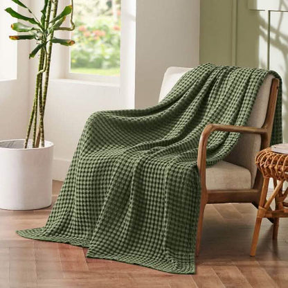 Olive green GentleSoft cooling waffle blanket draped on cream armchair, showcasing bamboo-cotton blend texture.