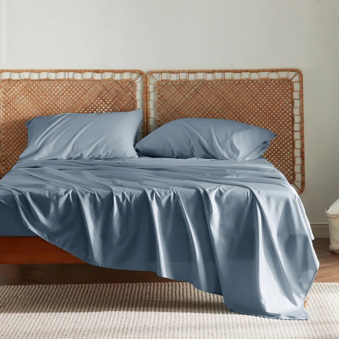 Silky soft blue rayon derived from bamboo sheet set on bed with rattan headboard.