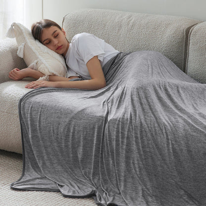 Woman sleeping comfortably on sofa under gray GentleSoft cooling blanket. Nylon. Comfort focus.