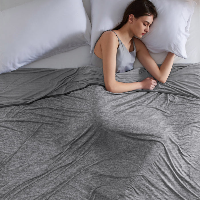 Woman sleeping under gray GentleSoft cooling blanket, showcasing comfort and cool nylon fabric.