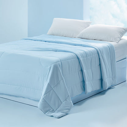 Light blue reversible cooling comforter with soft quilted texture on a bed.