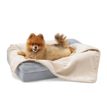 Fluffy Pomeranian dog lounging on a grey pet bed with a cream reversible Sherpa and microfiber fleece dog blanket.