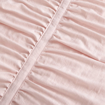 Pink polyester comforter close-up showing ruched fabric texture and decorative seam.